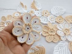 crocheted flowers are being held by someone's hand on a white table