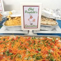 an assortment of food items displayed on trays at a buffet or catering event, including cheesy pizza and macaroni and cheese