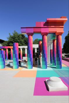 a colorfully painted building with columns and people standing in the doorways on either side