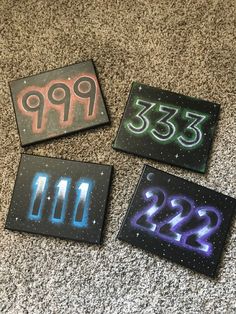 three square magnets with numbers painted on them are sitting on the floor next to each other