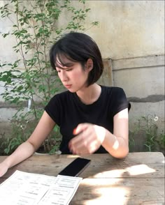 a woman sitting at a table with her cell phone in front of her and papers on the table