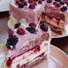 two pieces of cake with raspberries and cream frosting on plates next to each other