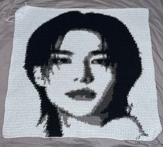 a crocheted portrait of a woman with black hair on a white blanket,