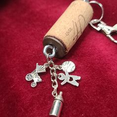 a cork keychain with charms attached to it on a red velvet surface next to a wine bottle