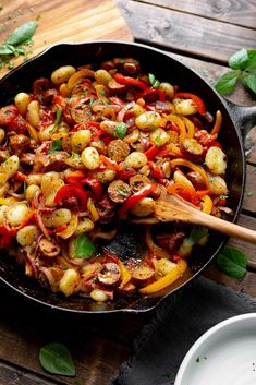 a skillet filled with vegetables on top of a wooden table