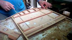 a man is cutting wood with a pair of scissors on top of the board that has been cut in half