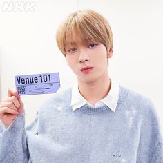 a young man holding up a sign that says venue 101 in front of his face