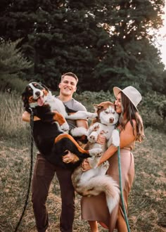 a man and woman holding dogs in their arms