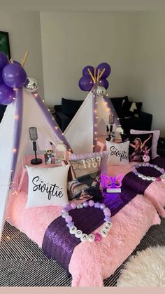 a bed topped with pillows covered in pink and purple blankets next to a teepee tent