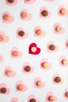 heart shaped cookies and macaroons arranged on pink hearts with red paper cutout