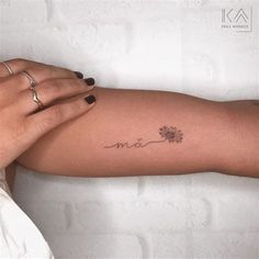 a woman's arm with a small flower tattoo on the left side of her arm