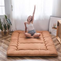 a woman sitting on an air mattress in the middle of a living room with her arms up