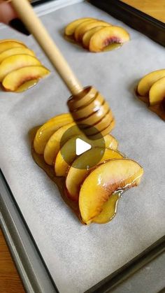 a pan filled with sliced peaches on top of a baking sheet next to a wooden spatula