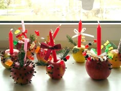 four apples with candles in them sitting on a table next to a window sill