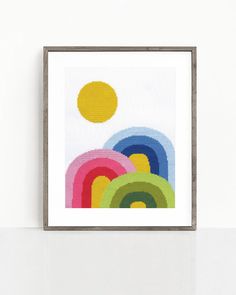 a cross - stitch pattern with rainbows and sun in the sky on a white wall