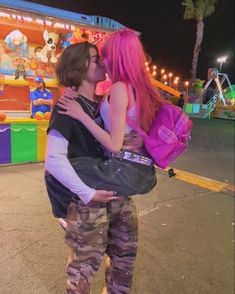 a man and woman kissing in front of a carnival ride