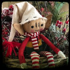 a stuffed toy elf sitting on top of a basket filled with pine cones and candy canes