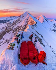 a red sleeping bag on top of a snow covered mountain