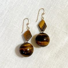 Tiger eye earrings with gold-filled findings. Handmade in Austin, Texas.  Over the past 30 years, I've enjoyed creating one-of-a-kind jewelry pieces using only the best materials: real gemstones and either sterling silver, gold-plated, or gold-filled findings.  If you see a design that you would like made with a different stone or findings, please do reach out so we can create your ideal piece. Likewise, please inquire about custom designs and I would be happy to work with you. Brown Sterling Silver Dangle Jewelry, Classic Brown Jewelry With Matching Earrings, Hypoallergenic Brown Sterling Silver Earrings, Unique Brown Round Earrings, Brown Gemstone Drop Earrings, Tiger Eye Earrings, Tiger Eye, Gold Filled, Jewelry Pieces