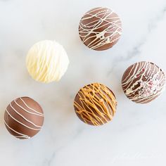 four different types of chocolates on a white marble surface with icing and sprinkles