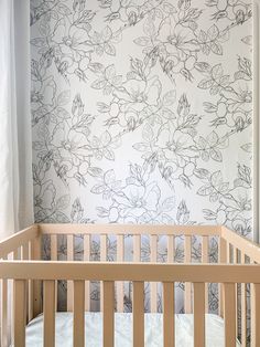 a baby's crib in front of a floral wallpaper