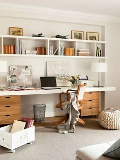 a home office with white shelving and wooden furniture