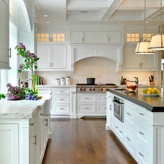 a large kitchen with white cabinets and wood floors