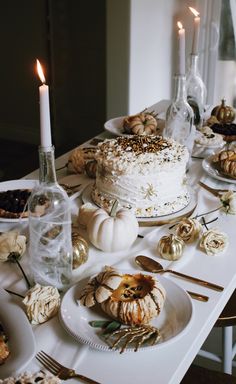 a white table topped with lots of food and candles