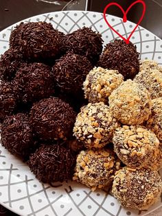 a white plate topped with chocolate covered donuts and sprinkles next to a red heart