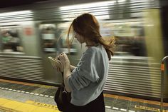 a woman is waiting for the subway to stop and look at her tablet computer screen