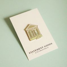 a white card with a small house pin on it's back that says statement goods