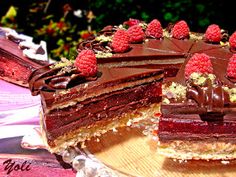 there is a chocolate cake with raspberries on the top and one slice missing