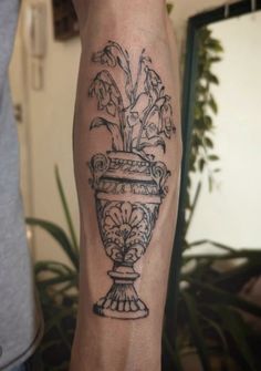 a black and white photo of a vase with flowers on it's arm, in front of a mirror