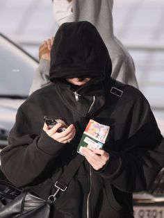 a woman in a black hoodie is looking at her cell phone