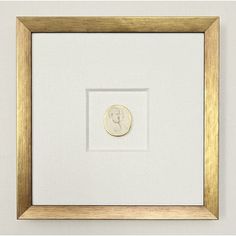 a gold and white frame with a button in the center on a white wall behind it