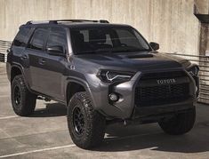 a gray toyota truck parked in a parking lot next to a building with concrete walls