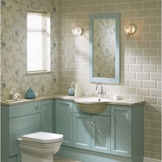 a bathroom with blue cabinets and a white toilet next to a sink under a mirror