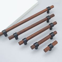 six pieces of wood with black handles on a white surface