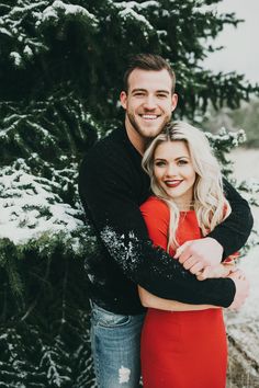 a man and woman hugging in front of snow covered trees