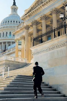 a man walking up some steps in front of a building with a dome on top