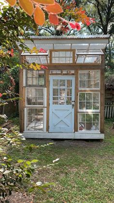 a small white shed with glass doors and windows