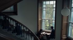 two people are sitting at a table in front of a window looking out the stairs