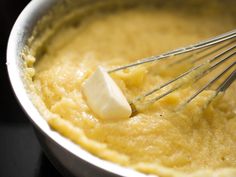 a metal bowl filled with yellow batter and whisk attachments on the side