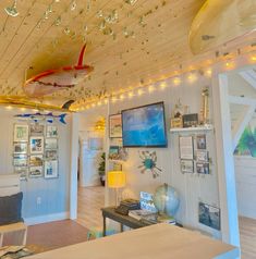 a living room filled with furniture and pictures on the wall next to a ceiling mounted surfboard