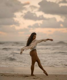 a woman standing on top of a sandy beach next to the ocean