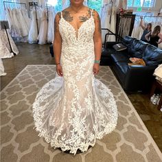 a woman in a white wedding dress standing next to a couch and looking at the camera