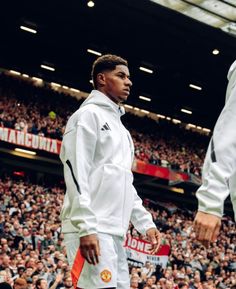 a man standing on top of a basketball court next to another man in front of a crowd