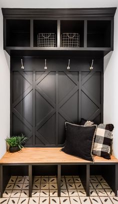 a wooden bench sitting under a coat rack next to a black shelf with two baskets on it