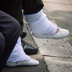 two people wearing white socks and black shoes