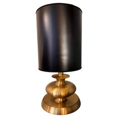 a black and gold table lamp with a black shade on the top, against a white background